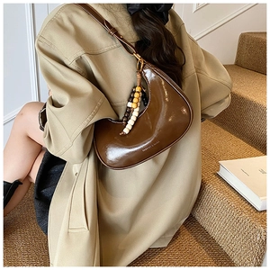 Detail of dark brown glossy patent leather hobo bag with colorful wooden bead charm