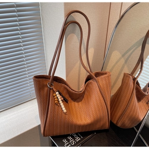 Detailed close-up of brown woven tote bag featuring an artistic beaded tassel accessory