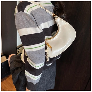 Close-up of white glossy hobo bag with vintage wooden beads and shoulder strap detail