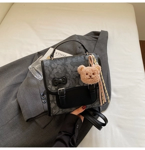 Detail view of vintage grey backpack with black leather trims and cute plush bear charm