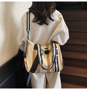Detailed shot of large striped canvas tote bag worn by a model on a modern staircase