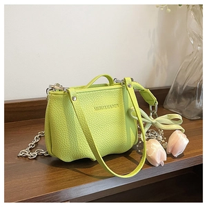 Détail du sac seau vert citron en cuir grainé avec chaîne et breloque fleurie