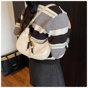 Detail shot of a white half-moon shoulder bag with colorful beaded tassel charms