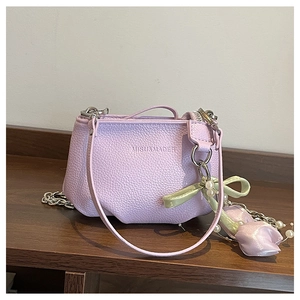 Détail du sac seau en cuir lilas avec chaîne argentée et décoration de nœud en satin
