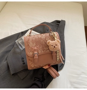 Detail of pink vintage handbag with floral pattern, leather trim and plush bear charm