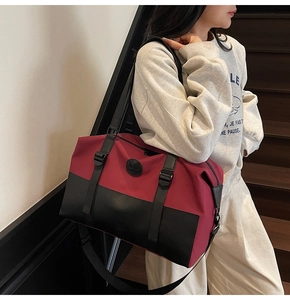 Close-up of red and black travel bag featuring waterproof nylon and leather handles