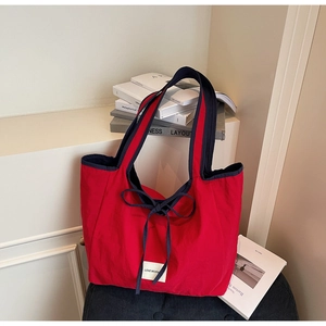 Detail of red canvas tote bag with navy blue handles and LOVE MORN woven label