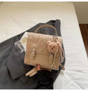 Detail of floral printed beige handbag on grey blazer with a cute plush bear charm