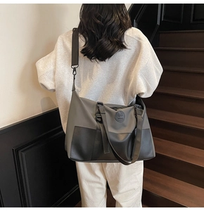 Detail of a large capacity waterproof nylon crossbody bag worn by a model on stairs