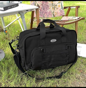 Detail of durable black travel bag with reinforced handles and multiple zipper pockets