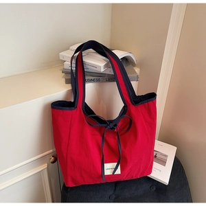 Close-up of red canvas tote bag featuring navy bow detail and textured fabric finish