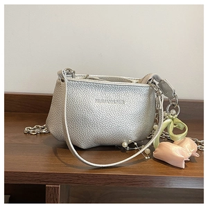 Détail du sac à chaîne argenté, texture grainée avec perles et nœud en soie décoratif