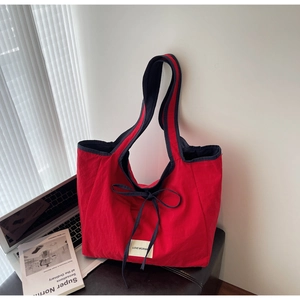 Detail of red canvas tote bag with black handles and Love Morning ribbon design