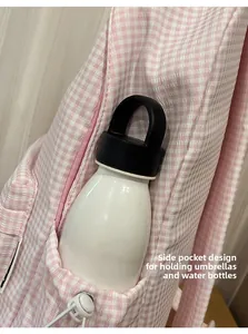 Détail de la poche latérale du sac à dos à carreaux roses avec cordon et gourde blanche
