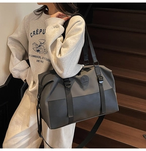 Detailed view of spacious grey crossbody travel bag with dual straps and round logo