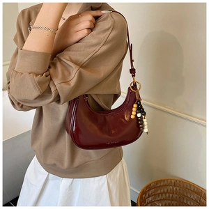 Detail of dark red half-moon bag with wooden bead tassel and fashion lettering