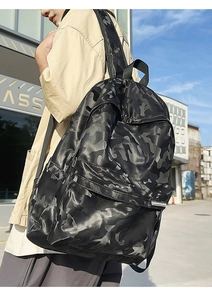 Detail of waterproof black camo backpack featuring sleek fabric and front pocket