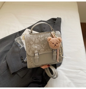 Close-up of gray-green backpack featuring white daisy prints and a leather bow detail