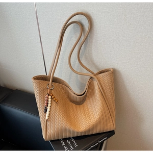 Detailed close-up of woven herringbone texture and wooden bead tassel on a tote bag