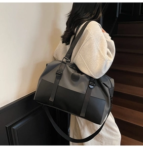 Detail of large-capacity grey canvas travel bag with leather handles shown on shoulder