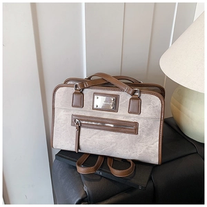 Close-up of stone-textured grey tote with brown leather trim and metal zipper pocket