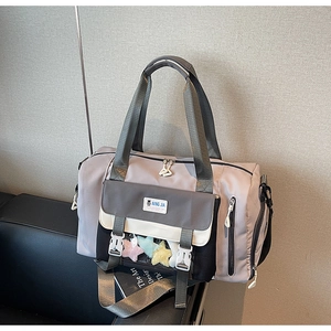 Dettaglio della borsa da viaggio lilla con logo e ciondoli a forma di stella colorati