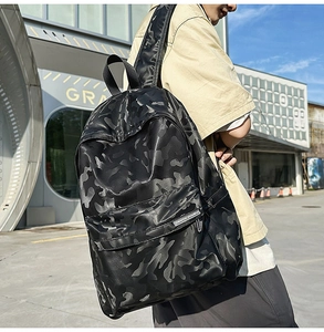 Outdoor shot of a black camo backpack with matte leather texture and front pocket