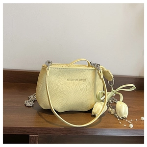 Gros plan du sac seau en cuir grainé avec charm tulipe et détail de chaîne en perles