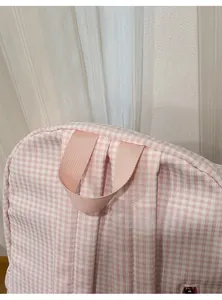 Détail de la poignée tissée rose sur un joli sac à dos à carreaux avec texture fine