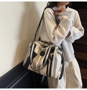 Close-up of striped canvas gym tote bag with leather logo patch and nylon strap