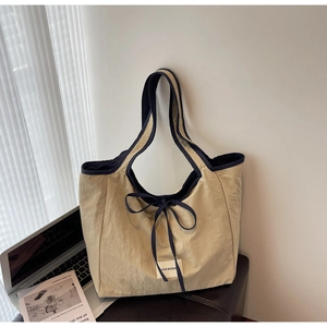 Detail of beige tote bag with blue trim, bow knot and Love Morning woven label