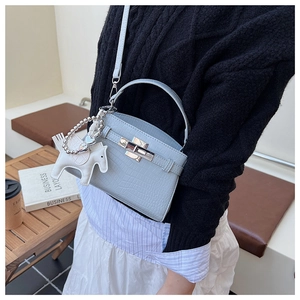 Close-up of light blue crocodile embossed texture and metal lock on luxury handbag