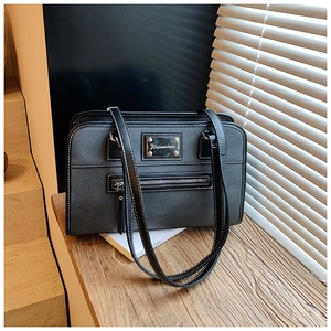 Detail view of contrast stitching and metal nameplate on the gray and black tote bag