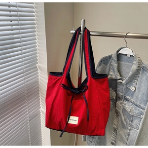 Detail of red tote bag featuring black shoulder straps and Love Morning logo tag