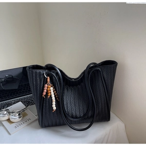 Detail of black woven tote bag featuring decorative bohemian wooden beaded charm