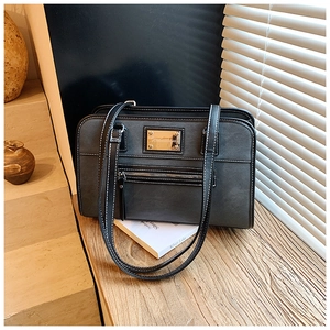 Detail of grey leather underarm bag featuring white contrast stitching and a metal nameplate