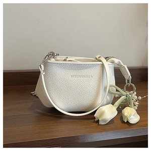 Détail macro du sac seau blanc en cuir grainé avec logo et pendentif tulipe