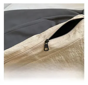 Macro shot of matte black metal zipper on textured beige nylon crossbody bag detail