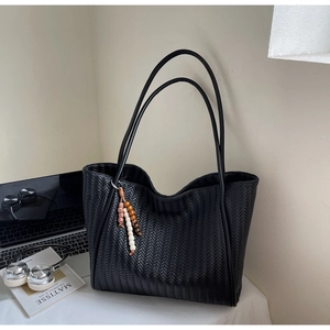 Detail of black woven tote bag with colorful beaded tassel and modern laptop background