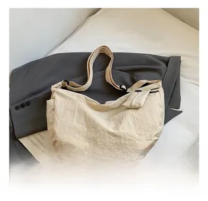 Detailed view of cream nylon crescent bag with adjustable strap and small coin purse attachment