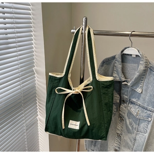 Detail of green tote bag with cream trim, bow accent and Love Morning label