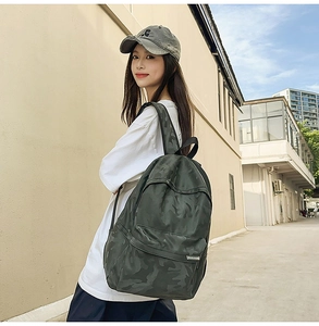 Detail view of large capacity camouflage backpack in deep olive worn by a model outdoors