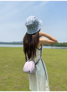 Bolso bandolera de nailon lavanda y gorro de pescador a cuadros azules al aire libre