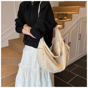 Detail of beige crescent crossbody bag showing textured fabric and brand label