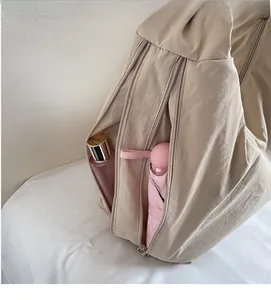 Detail of beige tote bag showing zippered pockets and spacious interior with essentials