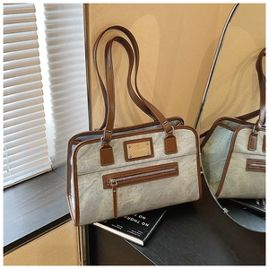 Detailed view of grey tote bag featuring brown leather trim and metal logo plaque