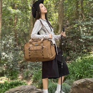 Close-up of khaki outdoor travel bag with elastic cords and zipper pockets in forest