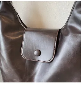 Dettaglio macro della borsa in pelle marrone con chiusura a scatto e cerniera in metallo