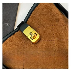 Détail du daim marron matelassé avec fermoir doré rotatif et bordure en cuir noir