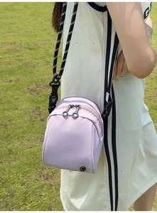 Detalle de bolso bandolera de nailon lila con cremalleras dobles y correa de cuerda tejida